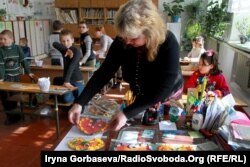 Классный руководитель раскладывает поделки учеников