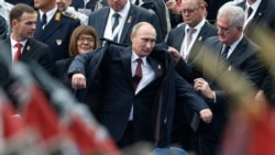 Vladimir Putin pred početak vojne parade u Beogradu, 16. oktobra 2014. godine. Mantil mu pridržava tadašnji predsednik Srbije Tomislav Nikolić.