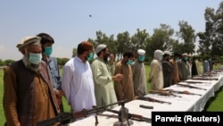 Disa talibanë duke dorëzuar armët e tyre.