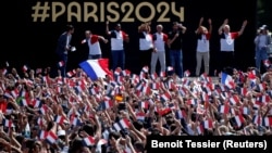 Ljudi se okupljaju u zoni navijača Olimpijskih igara u Parizu da gledaju ceremoniju zatvaranja igara u Tokiju, ispred Ajfelove kule, 8. avgusta 2021.