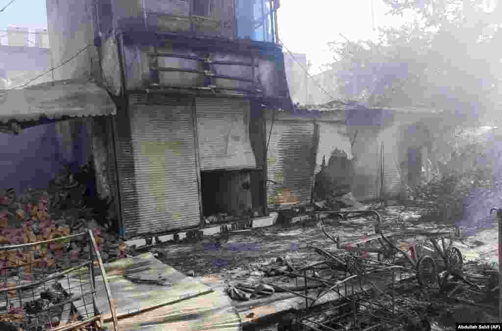 Damaged shops in the city of Kunduz were left smoldering after heavy fighting between Taliban militants and Afghan security forces.