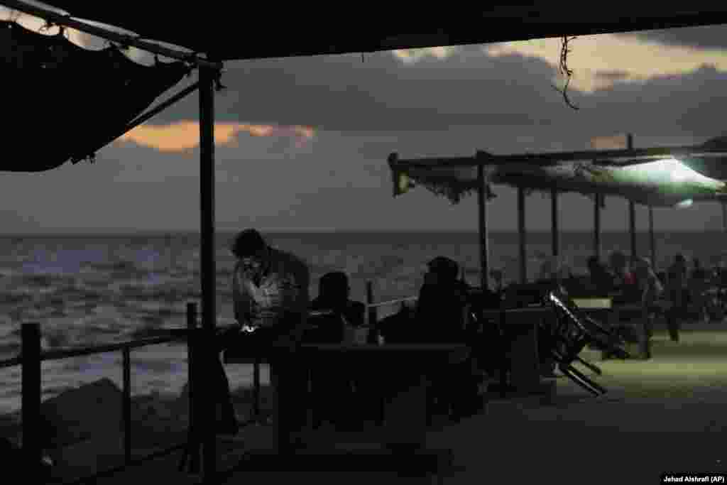 Një burrë palestinez duke shikuar telefonin e tij mobil, teksa pushonte buzë detit.