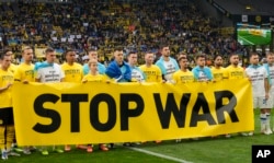 Jucătorii Borussiei Dortmund și echipei ucrainene Dinamo Kiev înaintea unui meci de Liga Campionilor din aprilie 2022, pe stadionul din orașul german. „Opriți războiul”.