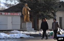 Жени вървят край статуя на Ленин в град Орловка, на 90 км от Бишкек, 11 март 2025 г.