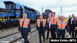 Sárváry István a kép bal szélén, Mészáros Lőrinc, Szijjártó Péter és Budai Gyula társaságában, a háttérben a V-Híd egyik csúcstechnikás vágányépítő gépe látható