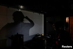 Un bucătar de la restaurantul La Cocinona din Madrid gătește la lumina lanternei telefonului mobil