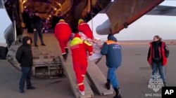 În această imagine difuzată de Serviciul de presă al ministerului rus pentru Situații de Urgență, salvatorii transportă un pasager rănit în apropierea orașului kazah Aktau, joi, 26 decembrie , 2024, după prăbușirea avionului Azerbaijani Airline.