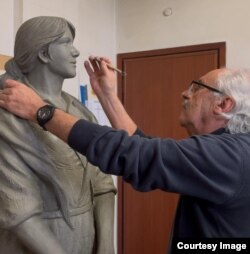 Sculptorul Mariani Guido retușează monumentul „Femeii Migrante”.