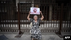 A Moszkvai Helsinki Csoport elnöke és a Kreml emberi jogi tanácsának tagja, Ljudmila Alekszejeva posztert tart fel a Duma épülete előtt 2015. május 29-én azzal a felirattal, hogy "Ellenzem a szadisták törvényeit".