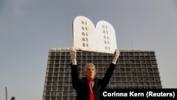 A „történelmi” új izraeli kormánykoalíciót egyfős többséggel szavazták meg a Kneszetben (61 voks a 120-ból) – erre emlékeztet a Mózes kőtábláit idéző kartonpapírral ez a Netanjáhú-maszkos tiltakozó