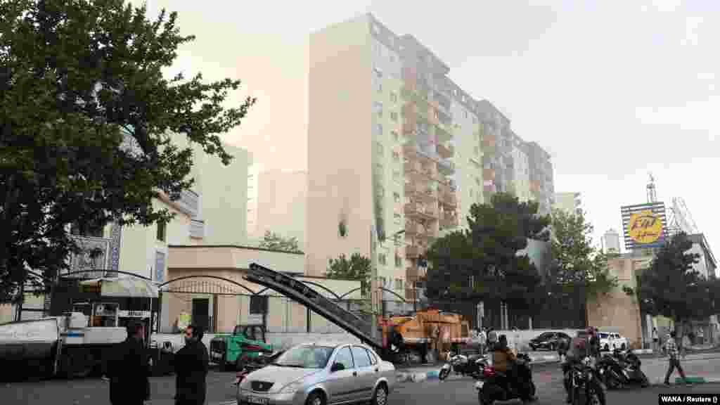 Njerëzit mblidhen rreth një ndërtesë të dëmtuar pas sulmeve izraelite në Teheran.