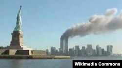 Ню Йорк, 11 септември 2001 г. Двете кули-близнаци на Световния търговски център горят, след като в тях се врязват самолети, управлявани от атентатори. На преден план е Статуята на свободата.