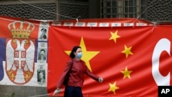 Një grua në Beograd kalon pranë një flamuri të Kinës. Foto nga arkivi. 