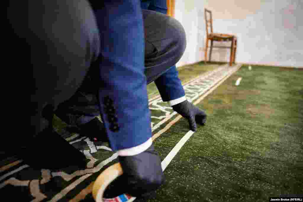 Glavni imam Čekrekčijine džamije Abdurahim Sultan na tepih stavlja oznaku za vjernike s ciljem poštivanja mjera fizičkog distanciranja.