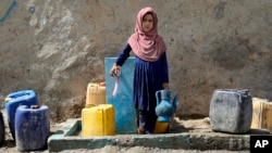 Афганистанско дете налива вода от обществена водна помпа в Кабул 