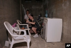 Două femei din Israel stau într-un adăpost din orașul Bat Yam din centrul Israelului, o zonă rezidențială lovită de o rachetă trasă din Iran, duminică dimineața, 15 iunie 2025.