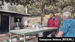 Стефан (вляво) е седнал пред изгорялата си къща заедно със свой съсед, 28 юли 2025 г.