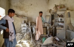 Bărbați afgani inspectează o casă avariată în urma unui atac aerian pakistanez în districtul Spin Boldak din provincia Kandahar, pe 15 octombrie.