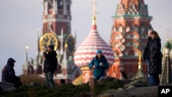 Люди гуляют в парке «Зарядье» на фоне Спасской башни Кремля и собора Василия Блаженного в Москве, 31 января 2025 года