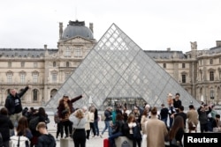 Хора се събират близо до стъклената пирамида на Лувъра в понеделник, когато музеят остана затворен заради обира. 20 октомври 2025 г.