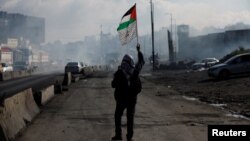 Čovek drži palestinsku zastavu, tokom sukoba Palestinaca s izraelskim snagama na okuipranoj Zapadnoj obali, 27. decembar 2022.