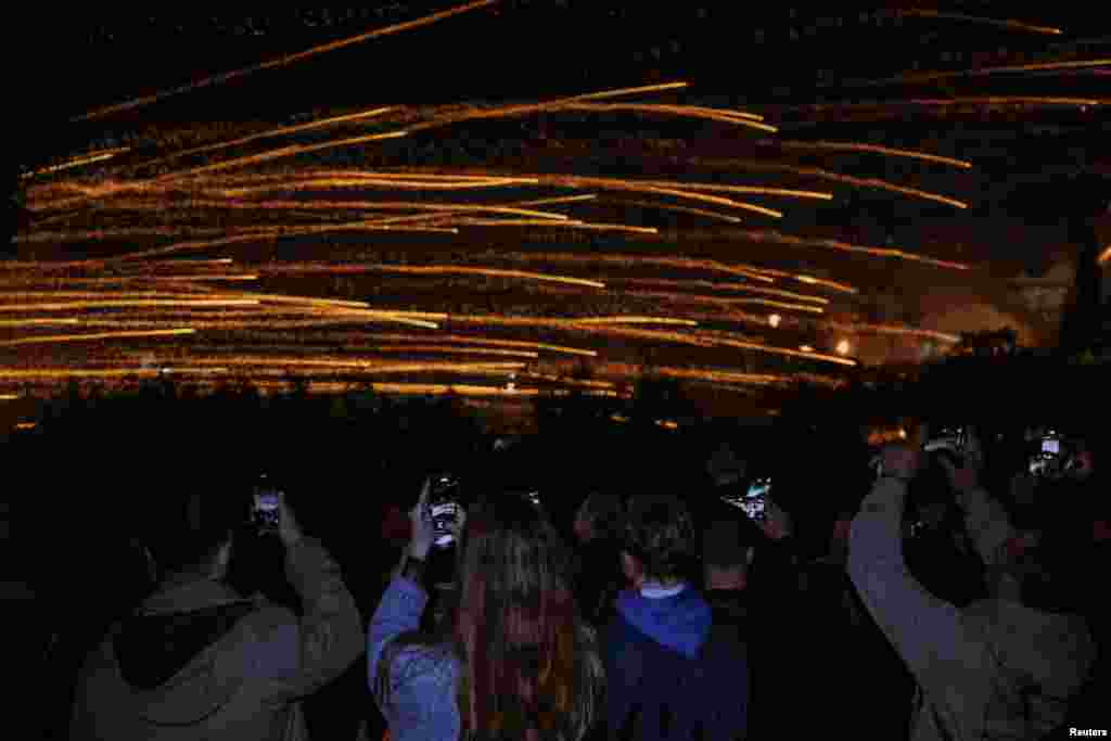 Ljudi fotografišu noćno nebo obasjano od ručno izrađenih raketa povodom proslave Uskrsa u selu Vrontados, na ostrvu Hios, Grčka, 19. aprila 2025.