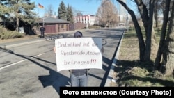 Пикетчик с видом на ворота посольства Германии. Слева можно увидеть направляющегося к нему от проходной полицейского. 