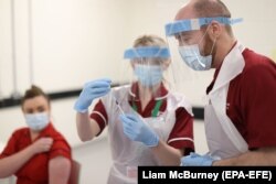 Punëtorët shëndetësorë duke u përgatitur që t'ia administrojnë vaksinën kundër COVID-19 një qytetareje.