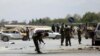 Afghan security forces inspect the site of a bomb explosion near a damaged vehicle in Kabul, April 27, 2020