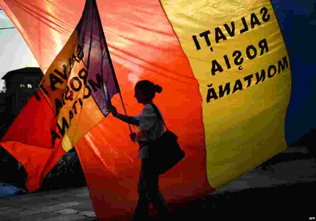Romania -- A protester holds a flag reading &quot;Save Rosia Montana&quot; during the eight day of demonstrations in Bucharest, September 8, 2013 