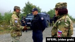 Një ushtare sllovene duke shikuar teksa një ushtar amerikan bisedon me një pjesëtarë të Policisë së Kosovës në Jarinjë. Fotografi nga arkivi.