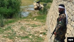 An Afghan soldier stands guard on a roadside in the Chahardara district of Kunduz.