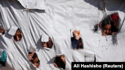 Djeca gledaju kroz rupe na šatoru u kampu Al-Hol u Siriji, april 2019. 