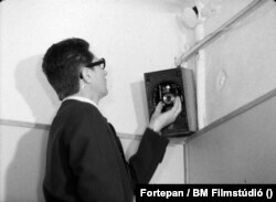 1962: Rejtett fényképezőgép telepítése egy irodai rádió hangszórójába. Képkocka a Belügyminisztérium Filmstúdiójának az álcázás technikai részleteit oktató filmjéből.