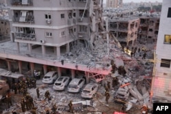 Echipele de intervenție lucrează printre dărâmăturile unei clădiri în urma unei lovituri cu o rachetă iraniană în orașul israelian Bat Yam, la sud de Tel Aviv, la începutul zilei de 15 iunie 2025.