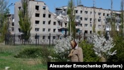 Žena u povratku sa obilježavanja Uskrsa prolazi pored zgrade oštećene u granatiranju, Avdijivka, Donjecka oblast, Ukrajina, 20. april 2025.