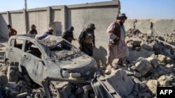 Membri ai forțelor de securitate talibane trec pe lângă o mașină avariată în districtul Spin Boldak din provincia Kandahar, pe 16 octombrie 2025, la o zi după ciocnirile de la graniță dintre Afganistan și Pakistan.