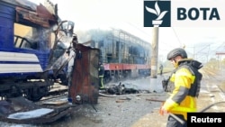 Një zjarrfikës shuan zjarret pasi një tren pasagjerësh u godit nga sulmet ruse me dronë në Shostka më 4 tetor 2025.