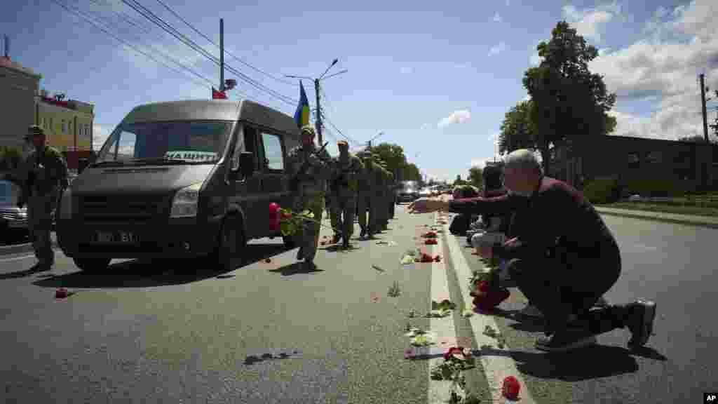 Stanovnici ukrajinskog sela Novi Petrivci bacaju cveće na put tokom pogrebne povorke Maksima Balueva, mladića iz kraja koji je poginuo u borbi sa ruskim trupama.