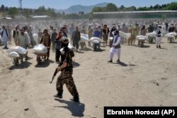 Luptători talibani supraveghează distribuirea de alimente aduse de un grup umanitar chinez la Kabul, aprilie 2022. Potrivit estimărilor, peste 1,1 milioane de copii afgani sub vârsta de 5 ani s-au confruntat cu foamete severă și malnutriție în 2022.