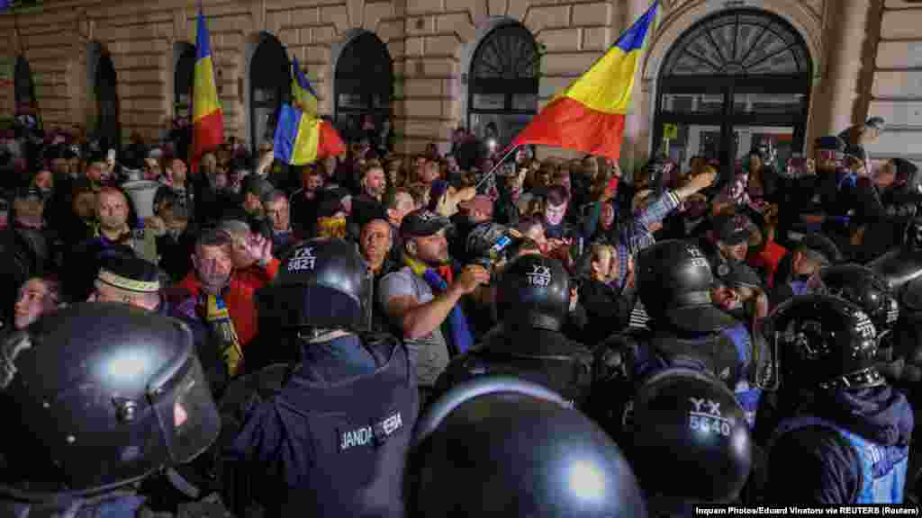 Călin Georgescu szélsőjobboldali jelölt támogatói a román központi választási iroda előtt a rohamrendőrökkel szemben 2025. március 9-én, miután elutasították az indulását Bukarestben &nbsp; 