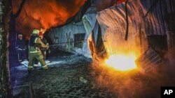 Pompierii încearcă să stingă un incendiu în urma atacului nocturn cu drone asupra orașului Harkov, 27 martie 2025.