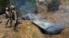 Pakistani soldiers stand next to what Pakistan says is the wreckage of an Indian fighter jet shot down in Pakistan-controlled Kashmir in the Somani area of Bhimbar district near the Line of Control on February 27.