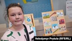 Стефания Есипенко, 10-летняя дочь фрилансера Крым Реалии Владислава Есипенко возле своего рисунка, где изображена ее семья. Киев, 5 июня 2025 года