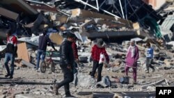 Ljudi prolaze pored srušene zgrade izbjegličkog kampa Al-Maghazi u centralnom dijelu Gaze, 16. januara 2024. godine