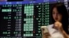 Žena pored ploče s prosječnim cijenama dionica na Tajvanskoj berzi u Tajpeju 7. aprila 2025.