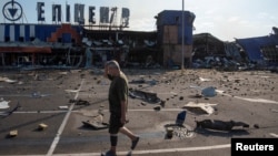 Маж поминува покрај трговски центар кој беше погоден од руски ракетен напад во градот Камјанск во украинскиот Днепарски регион на 26 јули 2025 година.