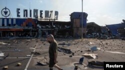 Një burrë duke kaluar pranë një qendre tregtare, që u godit nga një sulm me raketë ruse në qytetin Kamyanske, në rajonin e Dnjeprit në Ukrainë, më 26 korrik.