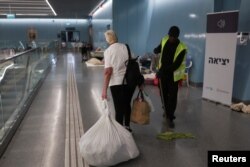 Žena nosi svoje stvari dok izlazi iz podzemne željezničke stanice koja je korištena kao sklonište od bombi, nakon što je na snagu stupilo primirje između Irana i Izraela, u Ramat Ganu, Izrael, 24. juna 2025.