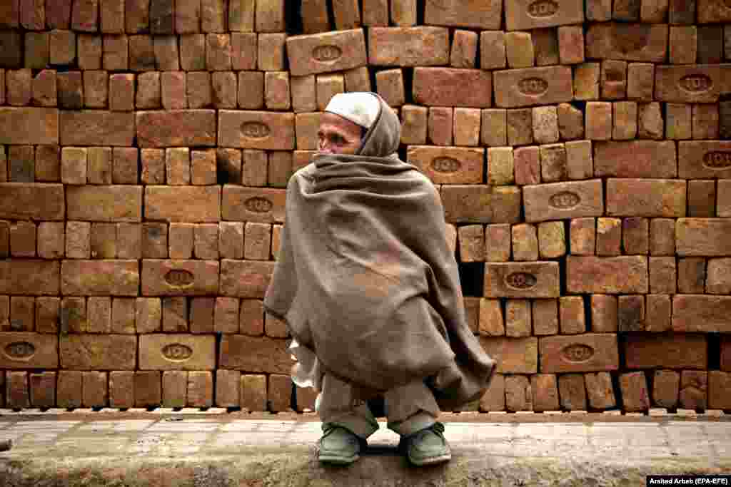 Pakistanac se pokrio tradicionalnim šalom kako bi se zaštitio od hladnog vremena na putu u Pešavaru. (epa-EFE / Arshad Arbab)